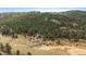 Aerial view of the property with a stream and meadow surrounding it in a lush forest at 7510 Blue Creek Rd, Evergreen, CO 80439