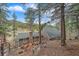 Exterior view of the home highlighting the stacked stone chimney and wood fence at 7510 Blue Creek Rd, Evergreen, CO 80439