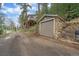 Charming stone one-car garage with rustic curb appeal and house in the background at 7510 Blue Creek Rd, Evergreen, CO 80439