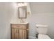 Cozy half bathroom with a wood vanity cabinet, gold fixtures, and modern lighting at 7452 W Cedar Cir, Lakewood, CO 80226