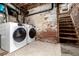 Basement laundry area features updated washer/dryer units and exposed brick wall near the stairs at 1776 S Logan St, Denver, CO 80210