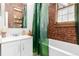 Cozy bathroom featuring a brick accent wall, a tub, and a stylish vanity at 1776 S Logan St, Denver, CO 80210