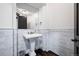 Powder room with marble tiled walls, pedestal sink, and black hardware at 46692 Silver Fir St, Parker, CO 80138