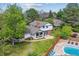 Aerial view of home featuring lush backyard, pool, stone patio, and mature trees under a bright blue sky at 6488 S Heritage E Pl, Centennial, CO 80111