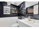 A modern powder room boasts a black marble accent wall, floating shelves, designer fixtures, and contrasting white wainscoting at 8291 S Krameria Way, Centennial, CO 80112