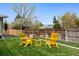 Well-maintained backyard with lush green lawn, privacy fence, and bright yellow Adirondack chairs at 7065 E Caley Ave, Centennial, CO 80111