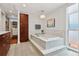 Bright bathroom featuring a soaking tub, and access to a walk-in closet and outdoor patio at 7065 E Caley Ave, Centennial, CO 80111
