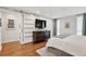 Bright bedroom featuring hardwood floors, a large bed, a wall-mounted tv, and an ensuite bathroom at 7065 E Caley Ave, Centennial, CO 80111