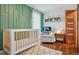 Bright Bedroom featuring a crib, comfortable chair, hardwood floors, and a modern design at 7065 E Caley Ave, Centennial, CO 80111