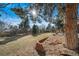 Large grassy backyard with brick retaining wall and mature trees at 5404 W Rowland Pl, Littleton, CO 80128