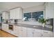 Bright kitchen featuring white cabinets, stainless steel appliances, and a large window with a view of the yard at 5404 W Rowland Pl, Littleton, CO 80128