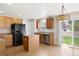 Bright kitchen features wood cabinets, an island, black appliances, and sliding doors to the fenced back yard at 9472 E 109Th Pl, Commerce City, CO 80640
