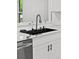 A modern kitchen sink has a black basin, stainless steel faucet, and quartz countertops with a white cabinet below at 1347 S Crystal Way, Aurora, CO 80012