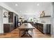 Open-concept dining area with long wooden table and chairs, hardwood floors, and modern lighting at 1601 Mariah Ln, Erie, CO 80516