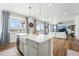 Kitchen island with white countertops, pendant lights, and living room in background at 1601 Mariah Ln, Erie, CO 80516