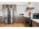 Contemporary kitchen with stainless steel appliances, quartz countertops, dark cabinetry, and hardwood floors at 1601 Mariah Ln, Erie, CO 80516