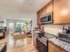 Open kitchen featuring wood cabinets, stainless appliances, and seamless flow into the living area at 2460 W Caithness Pl # 105, Denver, CO 80211