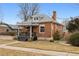 A charming brick single-story home with a walkway and covered front porch with gray railings and porch swing at 1452 S Emerson St, Denver, CO 80210