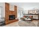 Open-concept living room with brick fireplace, wood floors, and a glimpse of the kitchen at 1206 E Phillips Pl, Littleton, CO 80122