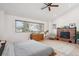 Cozy main bedroom featuring a brick fireplace, wood floors, a ceiling fan, and large window at 1206 E Phillips Pl, Littleton, CO 80122
