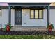 White ranch house with gray door, landscaping, and a covered entryway at 5519 Troy St, Denver, CO 80239