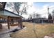 Large backyard featuring a covered patio, green grass, and mature trees offering ample shade at 2993 S Zenobia St, Denver, CO 80236