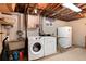 Functional laundry area includes a washing machine, dryer, and utility sink in the unfinished basement at 2993 S Zenobia St, Denver, CO 80236