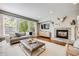 Bright and airy living room featuring hardwood floors, fireplace, and large windows with leafy outdoor views at 10590 Soulmark Way, Highlands Ranch, CO 80126