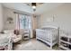 Bright Bedroom includes a crib, rocking chair, shelving, and natural light from the window at 2139 Coronado Pkwy # B, Denver, CO 80229
