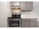 Stainless steel oven with gray cabinets, marble backsplash, and gray wood-look flooring at 10211 Ura Ln # 1-202, Thornton, CO 80260