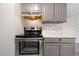 Close up view of an oven, marbled countertop, overhead cabinets, and stainless steel range hood at 10211 Ura Ln # 1-202, Thornton, CO 80260