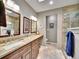 Luxurious bathroom featuring granite countertop, dual sinks, framed mirrors, and a tiled shower with glass door at 5231 S Cody St, Littleton, CO 80123