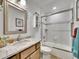 Bright bathroom featuring a granite countertop, framed mirror, and a shower-tub combination with sliding glass doors at 5231 S Cody St, Littleton, CO 80123