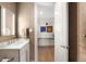 Modern bathroom with a sleek vanity, lit mirror, and textured wallpaper, looking into a bright hallway at 2400 E Cherry Creek South Dr # 209, Denver, CO 80209