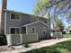 Two-story townhome with gray siding, stone chimney, and a well-maintained front yard under a clear blue sky at 8418 Everett Way # C, Arvada, CO 80005