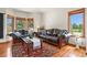 Bright living room with leather sofas, wood floors, and a view of trees through the windows at 937 Caribou Dr, Monument, CO 80132