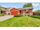 Inviting front exterior showcasing the home's red siding, brick foundation, and landscaped front yard at 5577 Jasper St, Denver, CO 80239