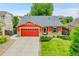 Charming red home featuring a well-manicured lawn, brick accents, and an attached two-car garage at 5577 Jasper St, Denver, CO 80239