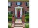 Elegant red front door framed by white columns, complemented by a black iron gate and manicured hedges at 6300 E 17Th Avenue Pkwy, Denver, CO 80220