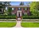 Charming brick home with a red front door, black shutters, manicured hedges, and a neatly landscaped front yard at 6300 E 17Th Avenue Pkwy, Denver, CO 80220