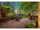 Inviting brick patio with a central fire pit, bench seating, and lush greenery, ideal for outdoor gatherings at 6300 E 17Th Avenue Pkwy, Denver, CO 80220