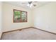 Bedroom with ceiling fan, carpet, wooden trim, and a large window overlooking trees at 4720 S Grant St, Englewood, CO 80113