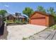 Exterior shot showcases the garage and the house, framed by mature trees and a blue sky at 4720 S Grant St, Englewood, CO 80113