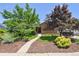 Beautiful brick home with mature trees, lush landscaping, and a welcoming walkway at 4720 S Grant St, Englewood, CO 80113