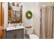 Updated bathroom with modern vanity, decorative wreath, and a shower with a colorful striped curtain at 4948 Cameyo Rd, Indian Hills, CO 80454