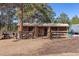 Exterior view of open stables, featuring a rustic wooden structure with individual stalls and farm equipment at 4948 Cameyo Rd, Indian Hills, CO 80454