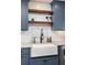 Close-up view of a farmhouse-style kitchen sink with open wood shelving and white subway tile backsplash at 4948 Cameyo Rd, Indian Hills, CO 80454