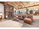 Spacious living room with stone fireplace, plush leather seating, and scenic outdoor views at 4948 Cameyo Rd, Indian Hills, CO 80454