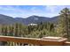 Breathtaking mountain view from the property's deck with mature evergreens and a bright, sunny sky above at 4948 Cameyo Rd, Indian Hills, CO 80454