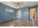 Empty bedroom with wood-look floors, closet, ceiling fan, window, and open doorway to bathroom at 7541 Julian St, Westminster, CO 80030